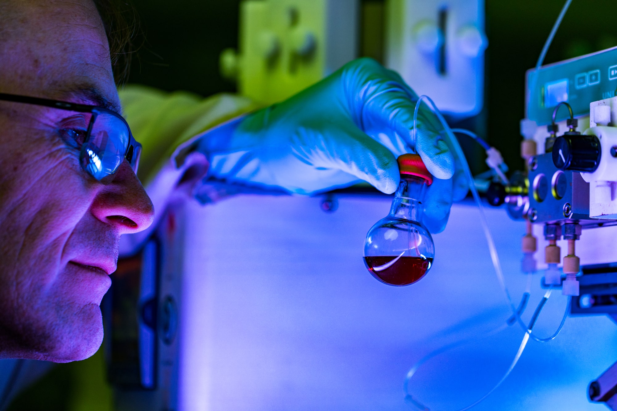 Scientist observering a red liquid in a glass container