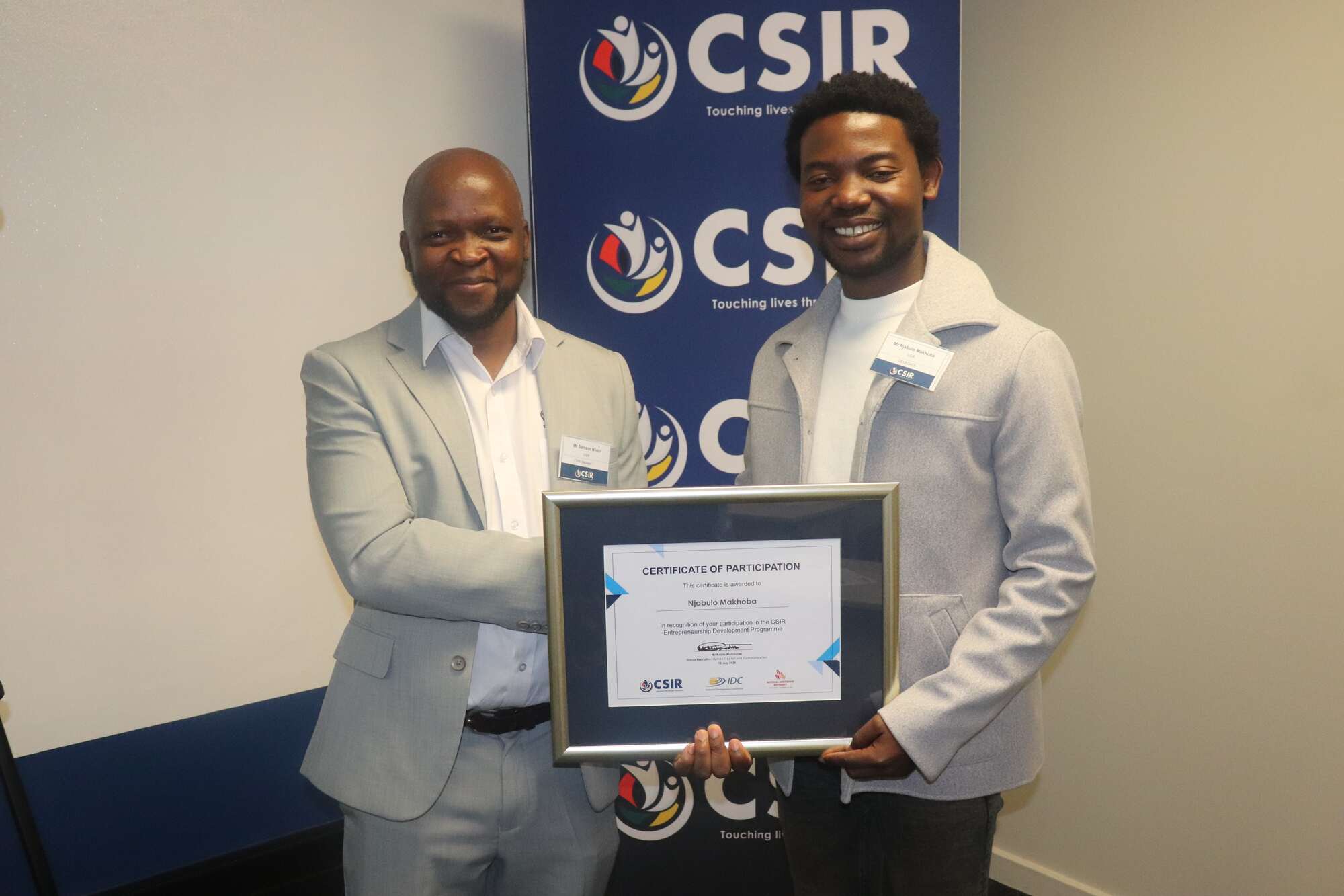 Two people smiling at camera and holding award