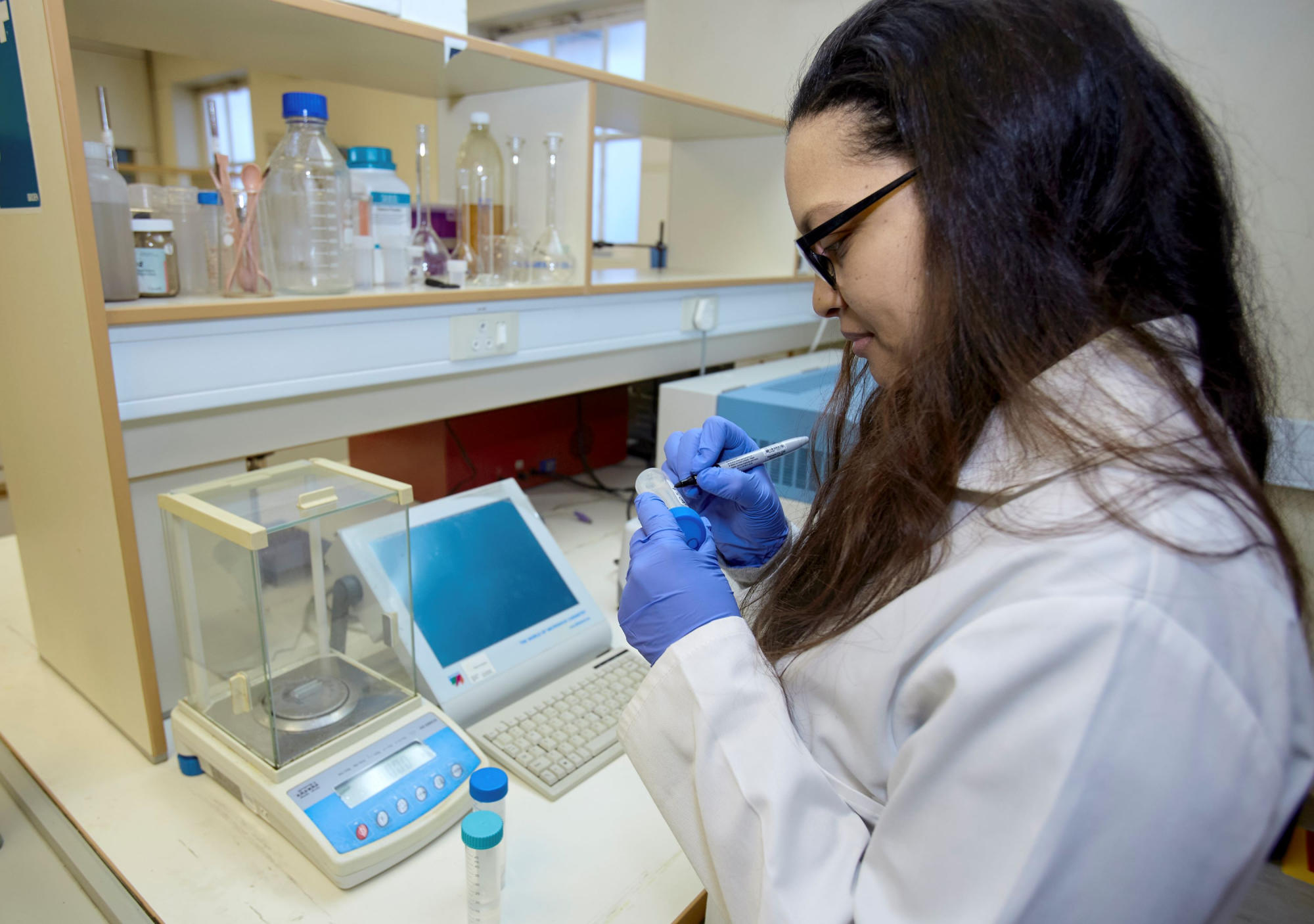 Hand holding a container with yellowish liquid