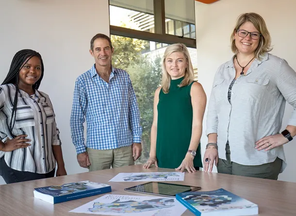 Four people facing a camera smiling